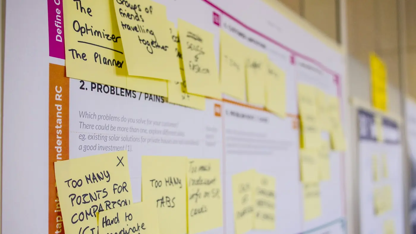 A workshop wall covered in sticky notes listing a project's problems and pain points