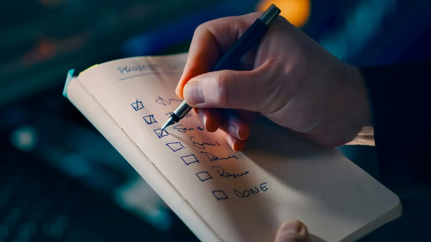 A hand ticking items off a to-do list in a notebook