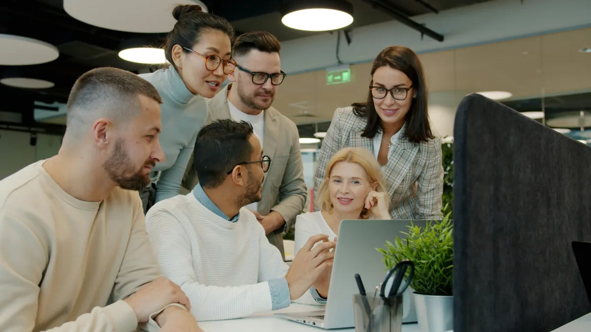 A team gathered around a laptop in an office, everyone taking part in the conversation