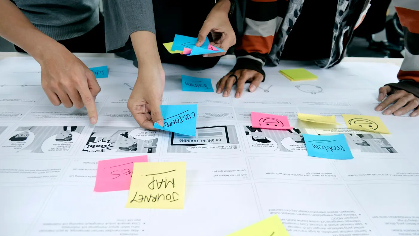 Several hands placing coloured notes onto a map laid out across a table