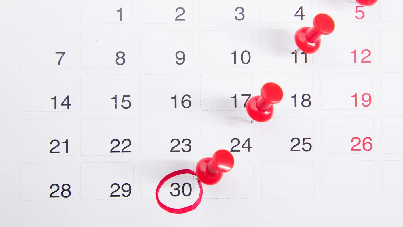 A calendar with red pins on several dates and the 30th circled